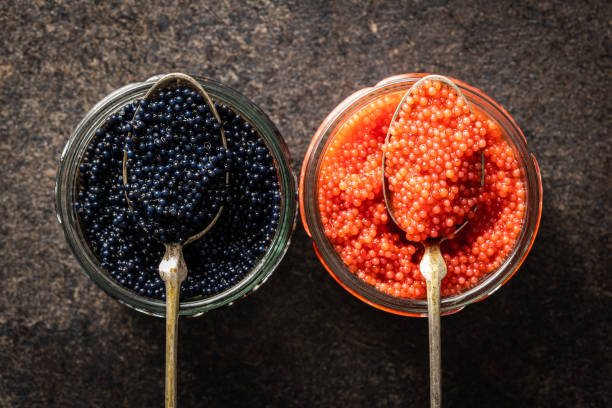 暗いテーブルの上に銀のスプーンで赤と黒のキャビア。 - caviar salmon red gourmet ストックフォトと画像