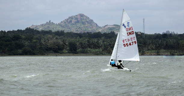 un piccolo yacht è visto navigare nelle acque agitate contro un paesaggio pittoresco vicino a mysore nel karnataka, in india. - rough waters foto e immagini stock