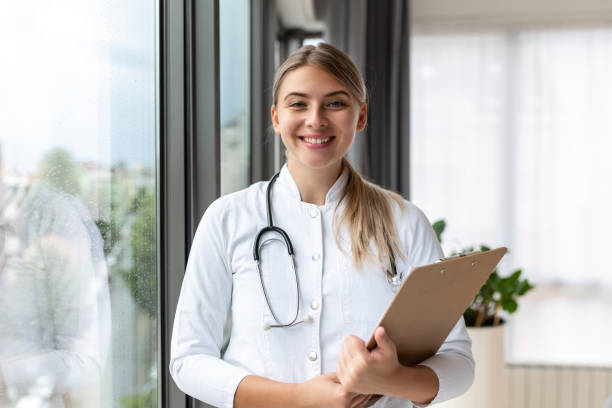 istock Confident smiling doctor posing and looking at camera with stethoscope in her hands. Friendly female doctor smiling. Doctor with stethoscope around her neck 1425424014
