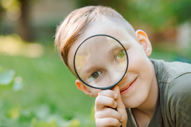 istock Caucasian Boy kid exploring nature environment with a magnifying glass loupe 1425425239