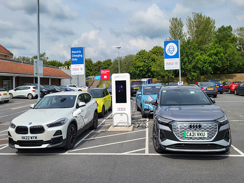 Swansea, UK: August 28, 2022: A BMW and Audi motor car are using a Pod Point charging station. Pod Point is a leading UK provider of charging infrastructure for electric vehicles - in partnership with Volkswagon and Tesco.