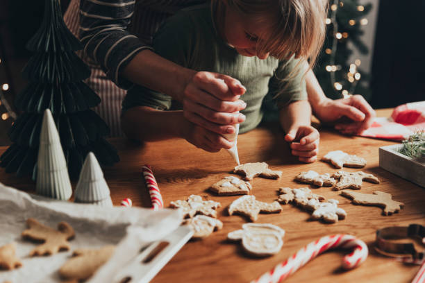 preparación de alimentos de navidad, año nuevo. galletas de jengibre decorando con glaseado - christmas child cookie table fotografías e imágenes de stock