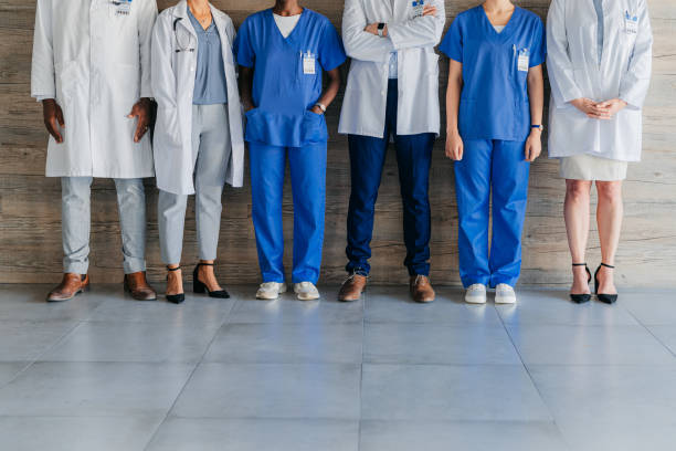 Team of professional, medical coworkers, against wood background, together show diversity, in hospital corridor. Group of doctors and nurses, against brown backdrop, in clinic or healthcare facility. stock photo