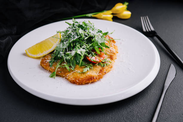 Traditional chicken schnitzel with arugula and lemon stock photo