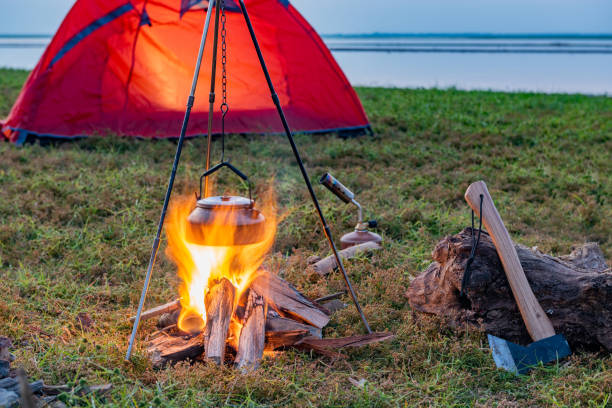 istock Campfire in orange tent camping on grass by lake 1425430671