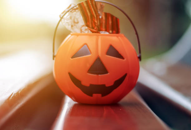 istock halloween pumpkin plastic bucket with candy sweets jelly worms kid hand 1425436313