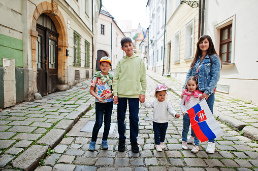 Mother with kids at street of Bratislava hold Slovakia flag.