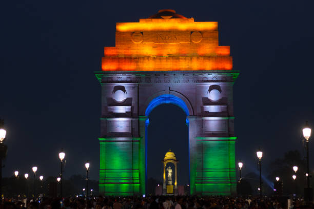 multidão de turistas à noite em tri color iluminou índia portão parte do trecho redesenvolvido da vista central em delhi - india gate delhi new delhi - fotografias e filmes do acervo