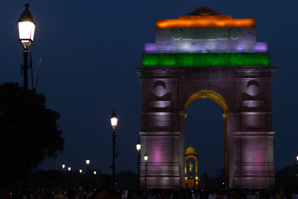 multidão de turistas à noite em tri color iluminou índia portão parte do trecho redesenvolvido da vista central em delhi - new delhi india night government - fotografias e filmes do acervo