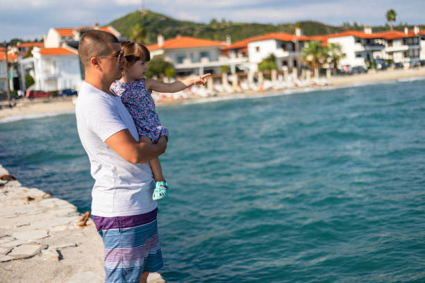 The little girl points her finger at the boats she sees in the distance.