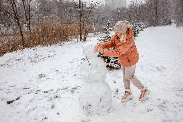 istock Woman makes a snowman in a city park during a snowfall 1425446021
