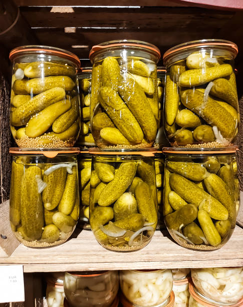 los pepinos en frascos se colocan en un estante de madera - pickle relish fotografías e imágenes de stock