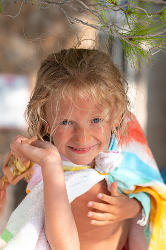 Portrait of a little girl with a stone in her hand. The child wears a terry towel on his shoulders.