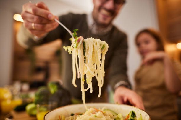 Close up of single father and daughter making spaghetti salad in the kitchen.