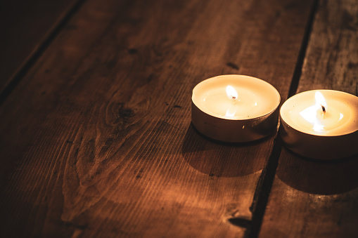 two burning candles on top of a brown wooden table, copy space.
