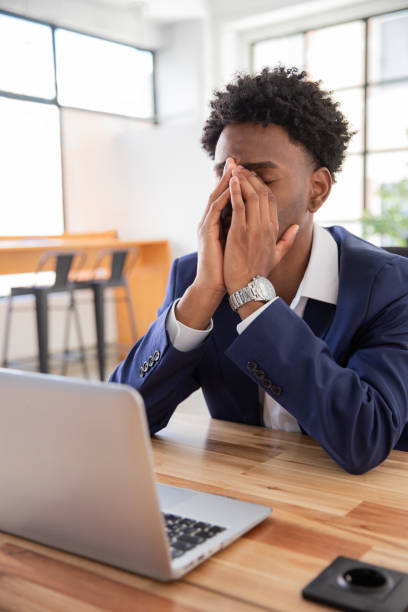 istock Portrait of young tired office worker at table rubbing nose 1425453633
