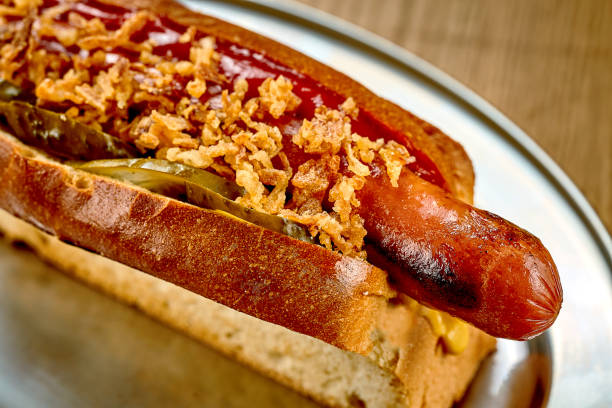 istock Hot dog with ketchup, caramelized onions. Close-up, selective focus. Noise added in post-production 1425455026