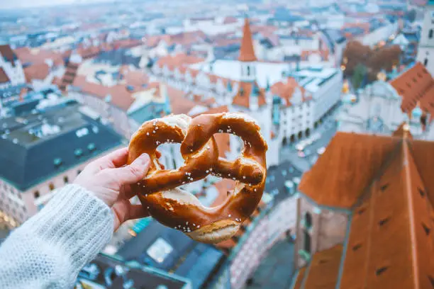Hand with pretzel on the background of the panorama of Munich. Germany in winter. High quality photo.