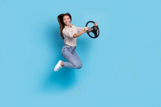 Photo of Full size photo of funny lady jump drive wear shirt jeans sneakers isolated on blue color background