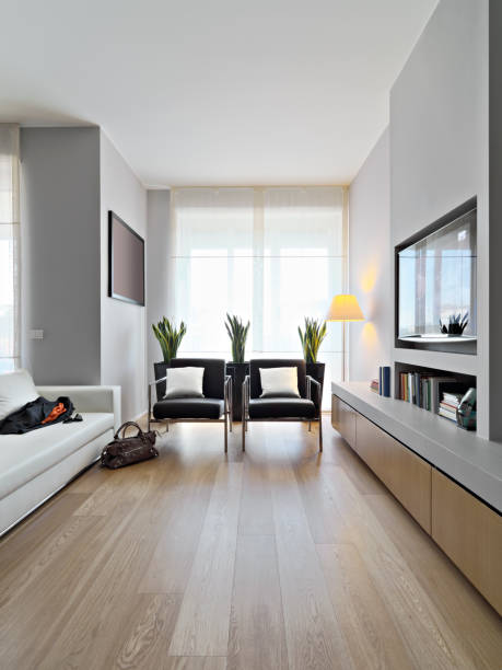 interiors shots of a modern living room in the foreground two leather armchairs and a leather sofa the floor is made of wood