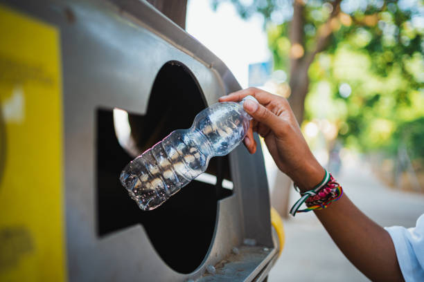 woman's hand holding an empty plastic bottle to throw it away - 循環再造 個照片及圖片檔