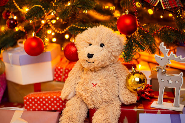 istock Teddy bear under decorated fir tree with many present boxes 1425462512