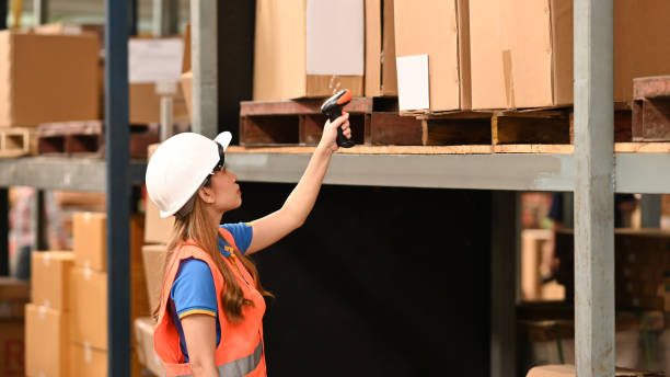 istock Female warehouse worker with barcode scanner checking inventory boxes on shelf in warehouse. 1425463104
