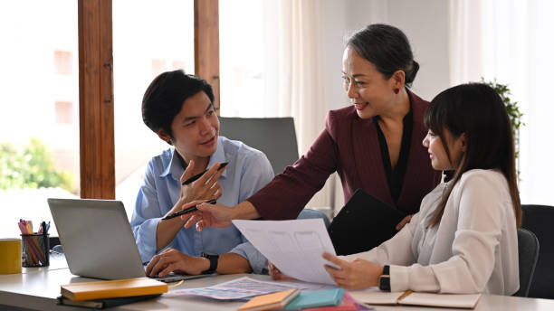 istock Smiling middle age female manager discussing new projects with young employees in bright office. 1425463277