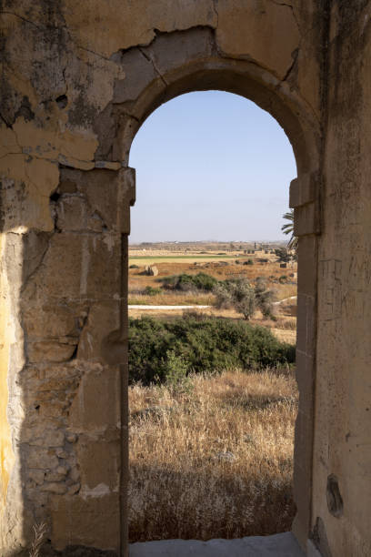 istock Bales in distant dry field viewed though window opening with arch in sandstone wall 1425463626