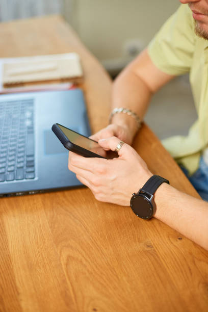 istock Businessman holding smartphone sitting in office, using cell phone mobile apps and laptop 1425463710