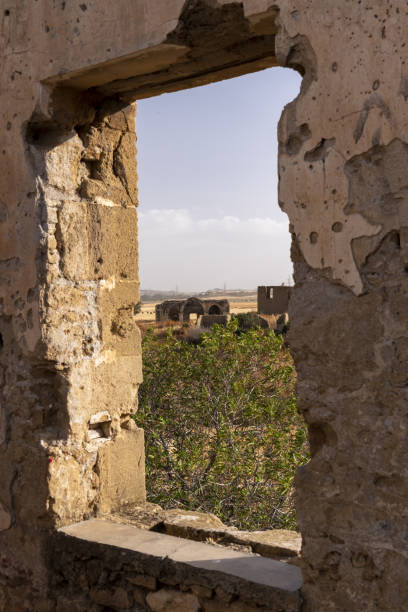 istock Distant church ruin viewed through window opening in shot-up sandstone building 1425465772