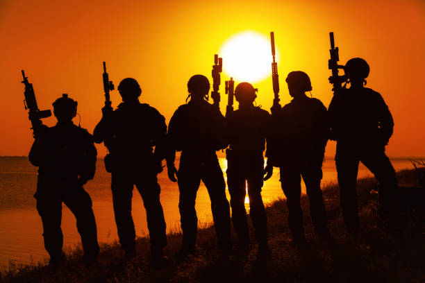 istock Army soldiers with rifles orange sunset silhouette 1425466472