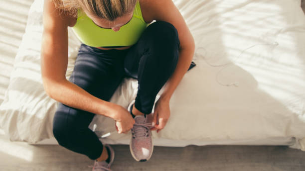 istock Female runner tying shoelace on bed at home 1425467421