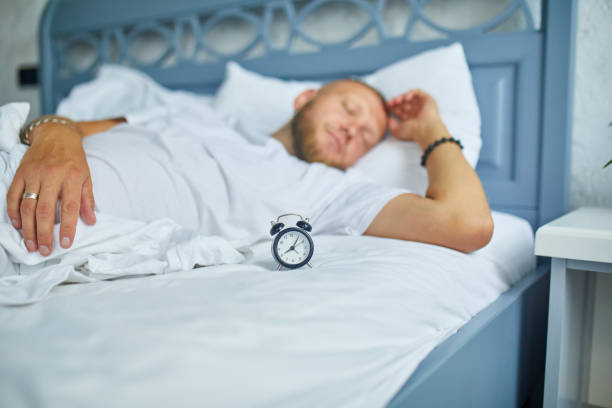 istock Bearded  man is sleeping alone on a big and cozy bed white linens with alarm clock at home, lifestyle, comfortable pillow, bed 1425468583