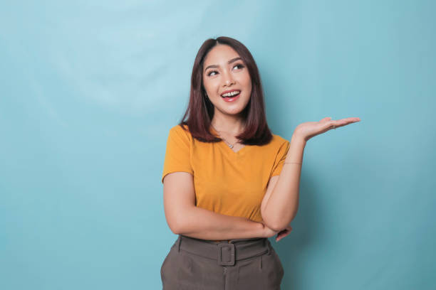 istock An excited young woman presenting and pointing copy space on her side, isolated on blue background 1425470228