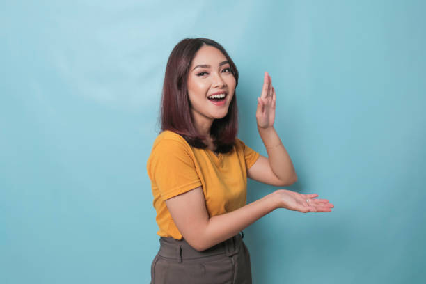 istock An excited young woman presenting and pointing copy space on her side, isolated on blue background 1425470248