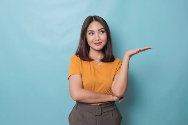istock An excited young woman presenting and pointing copy space on her side, isolated on blue background 1425470394