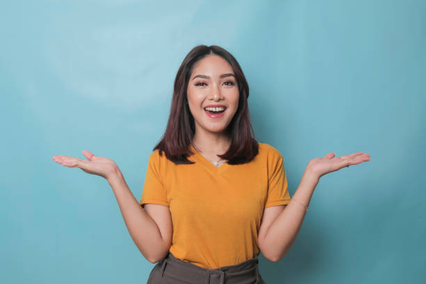 istock An excited young woman presenting and pointing copy space on her side, isolated on blue background 1425470437