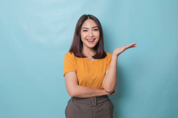 istock An excited young woman presenting and pointing copy space on her side, isolated on blue background 1425470448