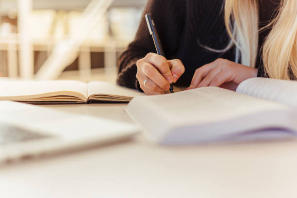 istock Caucasian female hands holding pen and taking notes while studying from books 1425470482