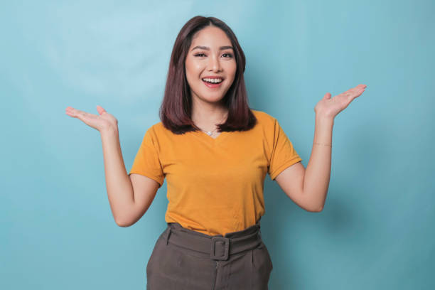 istock An excited young woman presenting and pointing copy space on her side, isolated on blue background 1425470507