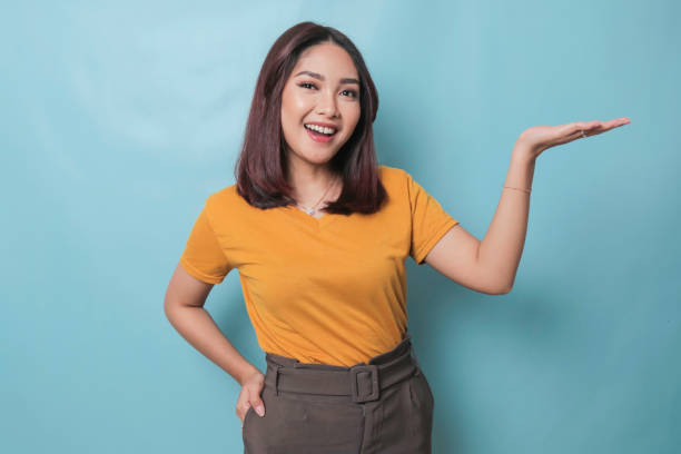 istock An excited young woman presenting and pointing copy space on her side, isolated on blue background 1425470540