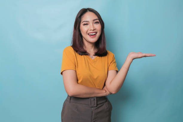 istock An excited young woman presenting and pointing copy space on her side, isolated on blue background 1425470565