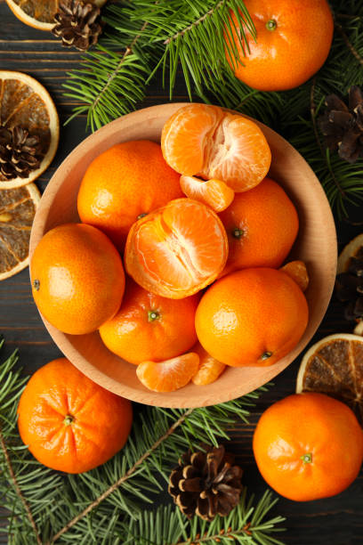 concepto navideño con mandarinas sobre mesa rústica de madera - mandarina fotografías e imágenes de stock