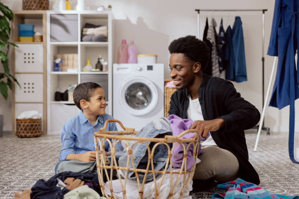 istock Son helps dad with household chores, man sort laundry, fold clothes, prepare for drying, spend time together in the bathroom teaching the girl how to use the washing machine 1425474345