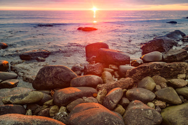 Beautiful Midnight sun sunset over rocky ocean shoreNorth Iceland
