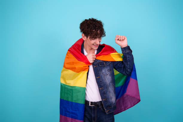 jovem atraente com uma bandeira de arco-íris. - flag gay man american culture rainbow - fotografias e filmes do acervo