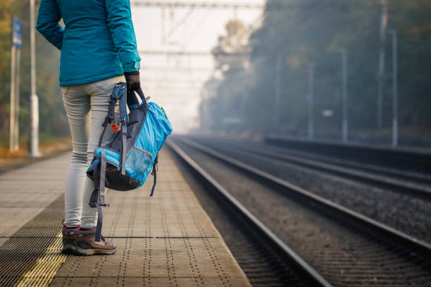 frau mit rucksack steht auf leerem bahnhof - leaving loneliness women railroad track stock-fotos und bilder