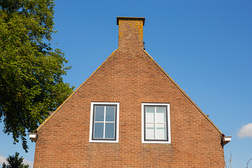 House wall with two windows against blue sky