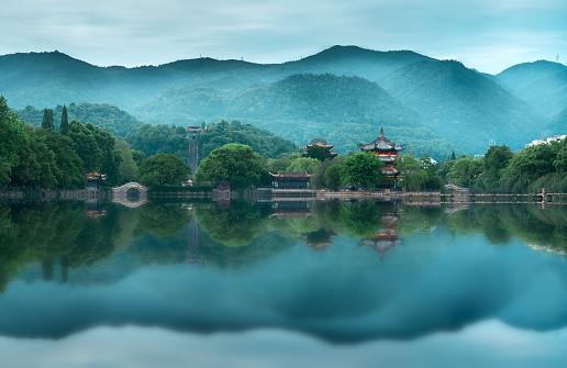 Chinese pavilions and small bridges in the fog form a perfect reflection in the lake